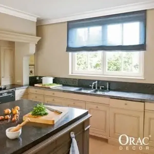 Modern kitchen with beige cabinets, dark countertops, and blue Roman shade window treatment.