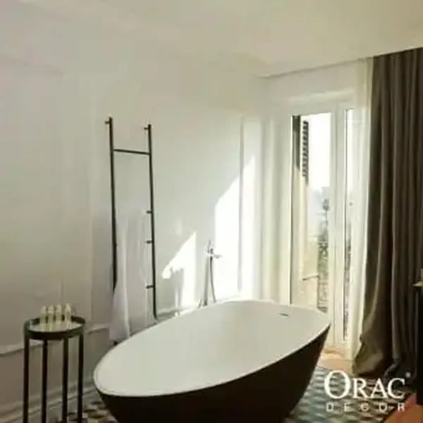Bathroom corner with Orac C333 coving and freestanding bathtub in a modern, light-filled bathroom