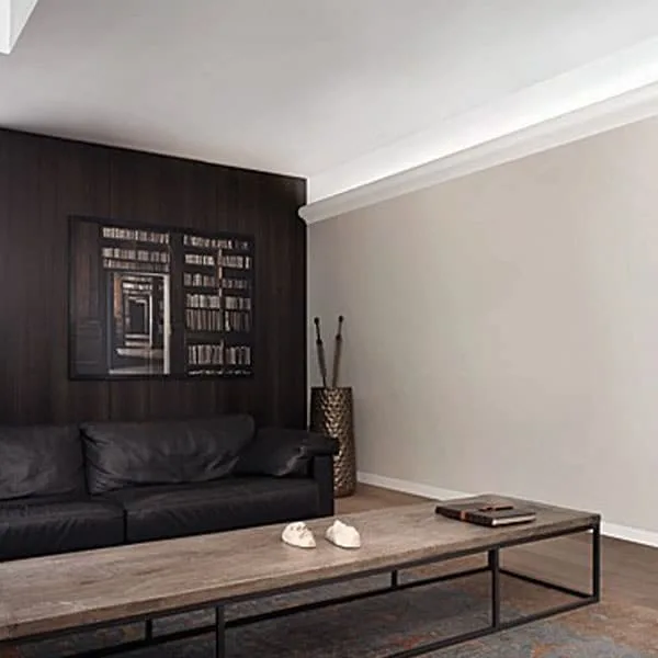 Panel moulding in corner of modern living room above black leather sofa, Orac C333 painting edge profile