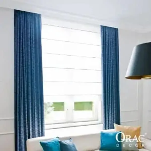 Modern living room corner with blue curtains, white Roman shades, and white coving in place.