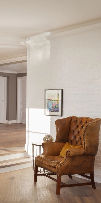 Orac Decor C902 Coving in a room corner, shown with a leather armchair and yellow pillow