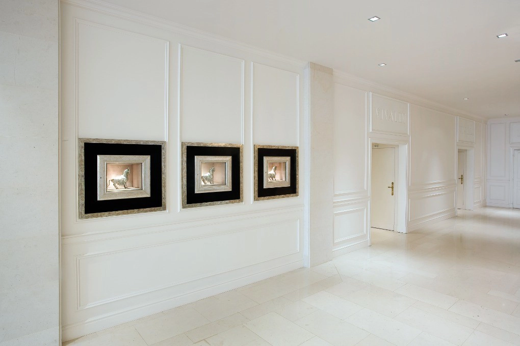 Orac CX124 skirting in a minimalist white hallway with framed wall art