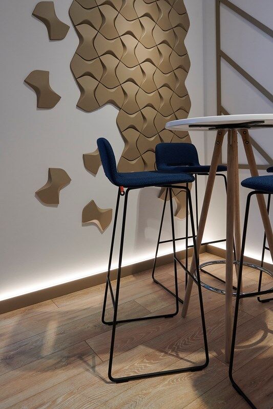 Modern bar stools with blue cushions and geometric wall art in a stylish interior setting