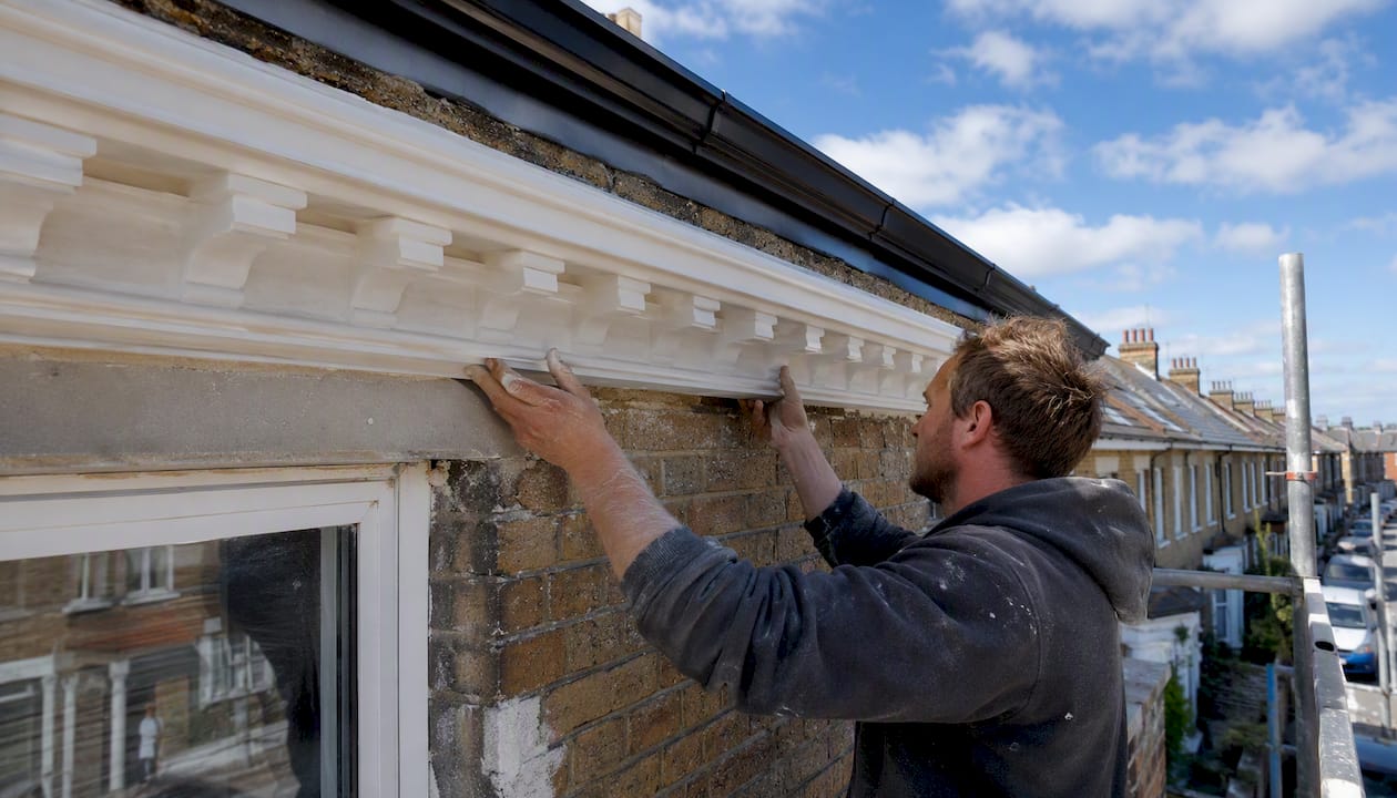 Hands installing cornice and dentil polyurethane mouldings