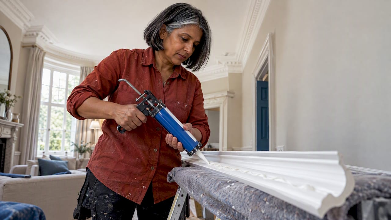 Installer applying adhesive to polyurethane coving